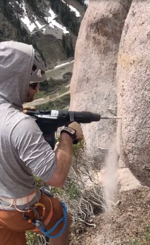 Construction worker drills a hole into rock for the Tahoe Via Ferrata