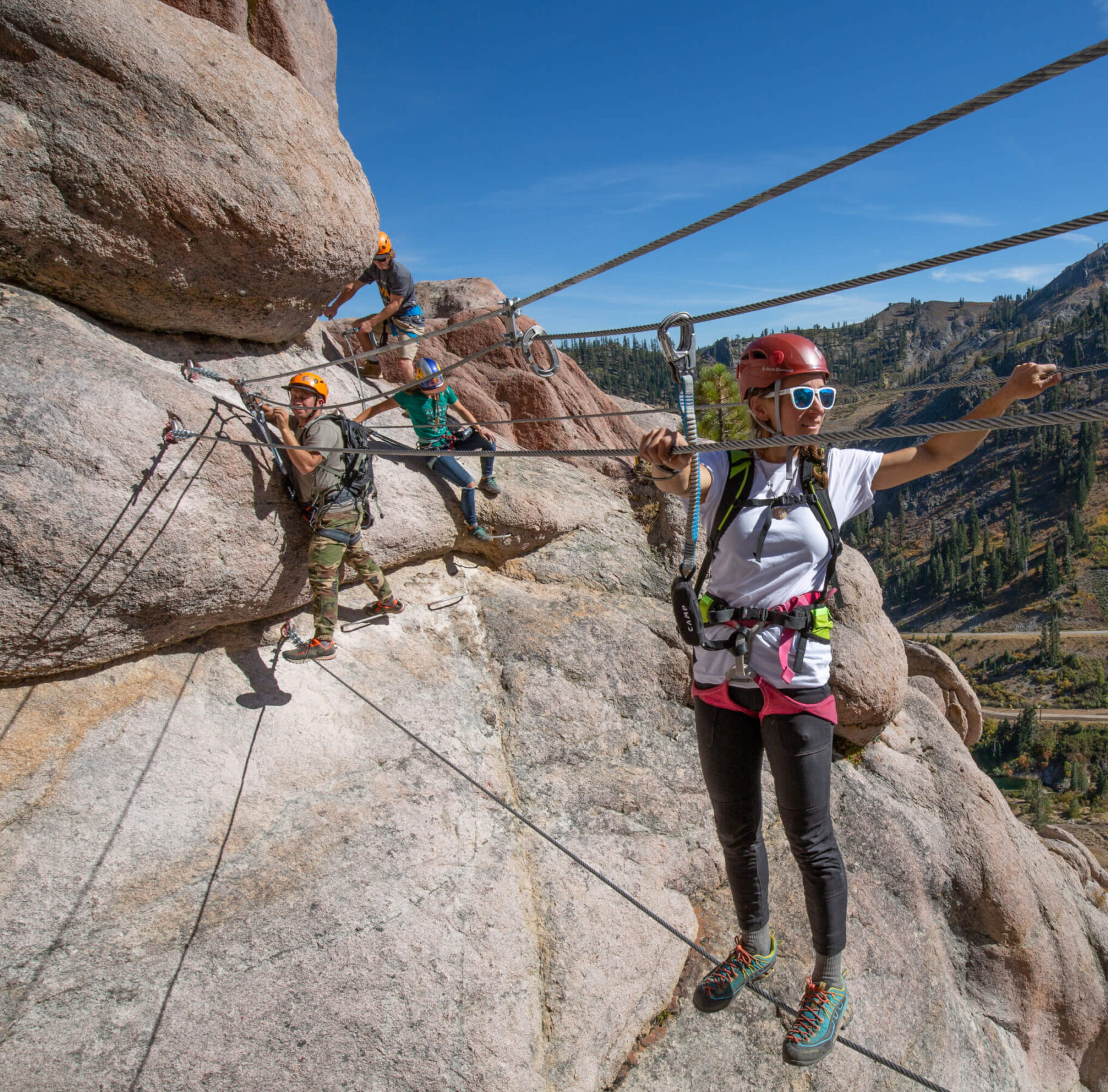 A group of climbers crossing a monkey bridge on the Tahoe Via Ferrata at Palisades Tahoe in Olympic Valley. One of the best Lake Tahoe adventures!