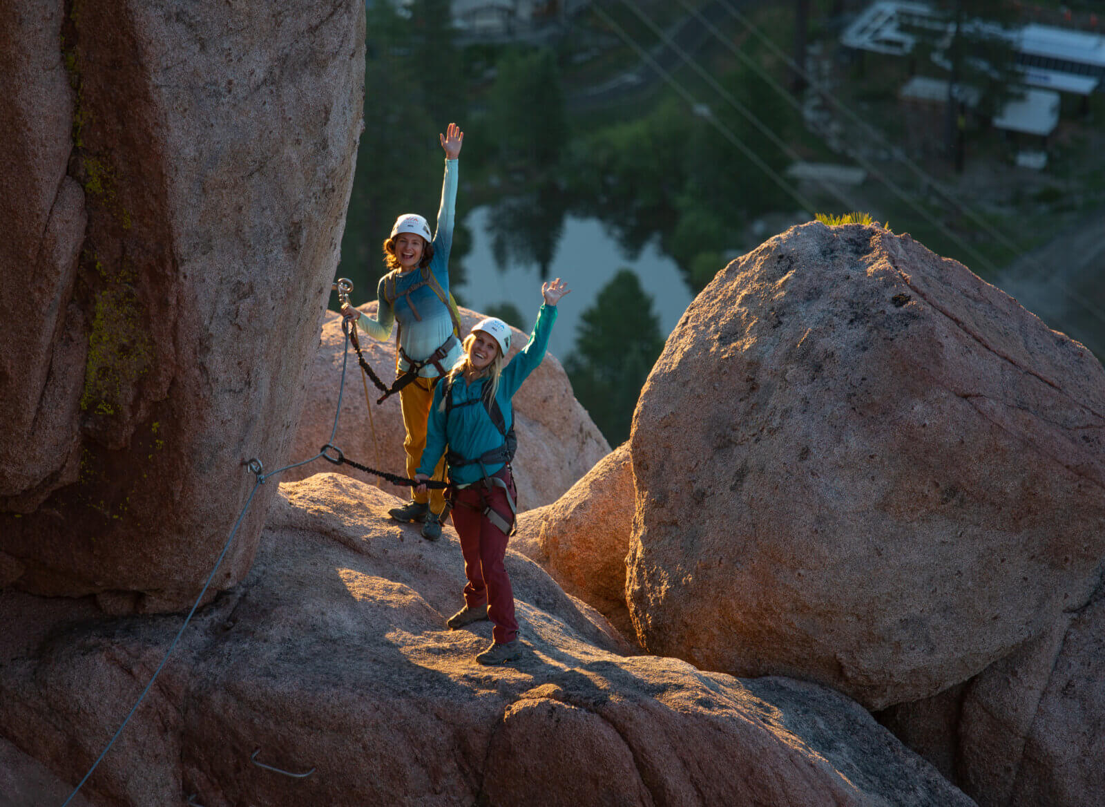 Two climbers on the Tahoe Via Ferrata waving to the camera during sunrise. One of the best Lake Tahoe adventures!