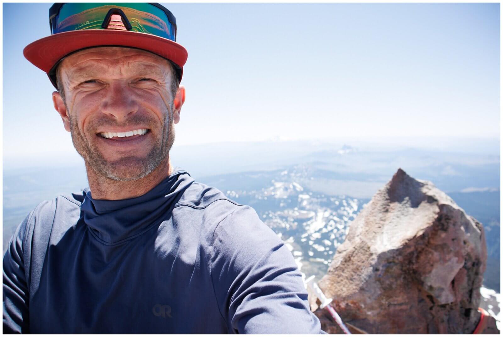 Alpenglow Expeditions' Tahoe Via Ferrata guide Carl Davis standing on the summit of a peak.